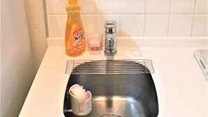 En vask med opvaskestativ, en sæbeflaske og en sæbedispenser.