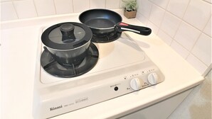 Et køkken med en hvid komfur, to sorte gryder og en lille plant i en potte på bordet.
