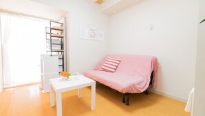 Una habitación luminosa con una mesa blanca, un sofá rosa y un radiador blanco.