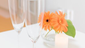 Dos copas de champán y una vela con una flor sobre una mesa.