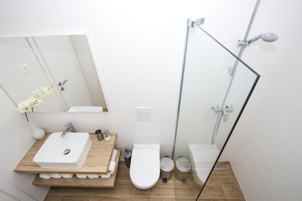 Une salle de bain moderne avec une douche à parois de verre, un meuble-lavabo en bois et des toilettes.