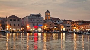A waterfront scene with buildings, a tower, and boats reflecting on the water.