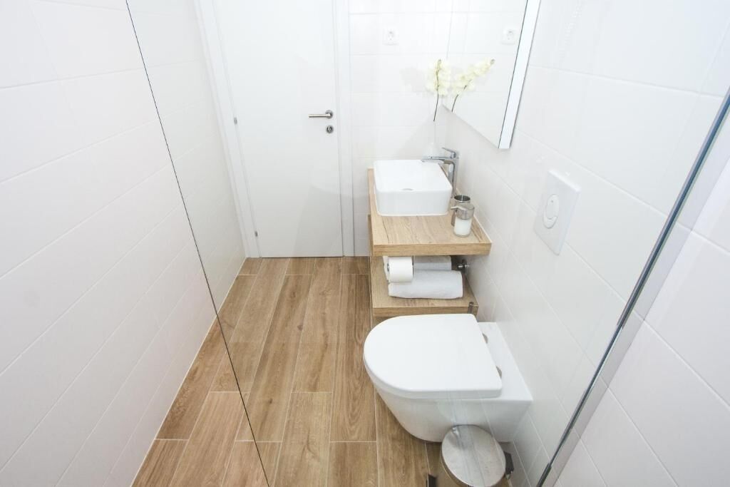 A small, modern bathroom with a toilet, sink, and shower area.