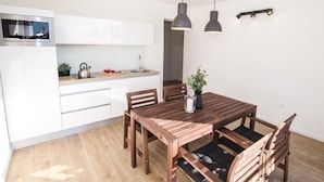 Una cocina moderna con armarios blancos, horno empotrado y una mesa de madera con sillas.