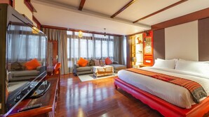 A hotel room with a large bed, a TV, a sofa, and a coffee table.