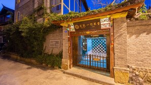 A traditional Chinese building with a wooden gate and a sign indicating it is a hotel.