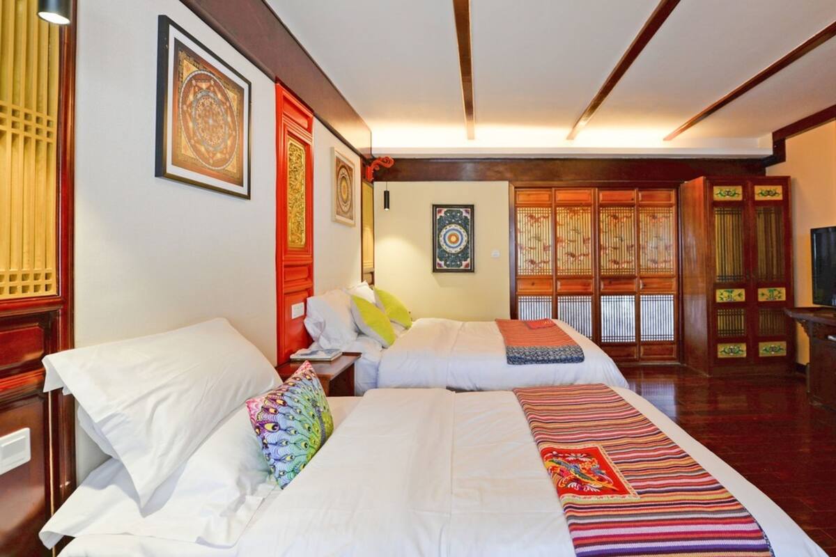 A hotel room with two beds, a television, and traditional decor.