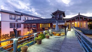 A traditional building with a wooden deck, potted plants, and a railing.