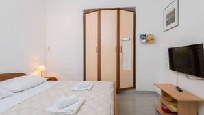 A hotel room with a bed, a wardrobe, a TV, and a bedside table with a lamp. - Studio apartment in Orebić with Terrace, Air condition, WIFI (4934-2) (Orebic)