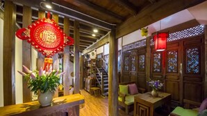 A traditional interior with wooden furniture, a staircase, and decorative elements. - Flowers without Boundary Inn (Lijiang)