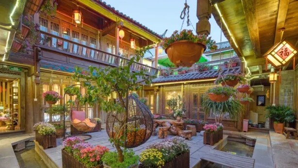 A traditional courtyard with wooden structures, hanging planters, and a central seating area. - Flowers without Boundary Inn (Lijiang)