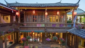 A traditional Chinese courtyard with wooden architecture, multiple balconies, and hanging lanterns. - Flowers without Boundary Inn (Lijiang)