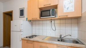 Pieni, käytännöllinen keittiö, jossa on mikroaaltouuni, pesuallas ja pieni liesi.