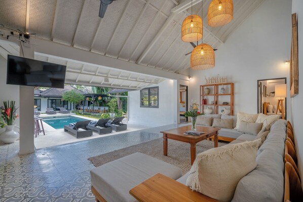A spacious living area with a pool view, modern furniture, and a flat-screen TV. - LARGE GROUPS, 10 BDR, NR BEACH, GREAT INCLUSIONS (Seminyak)