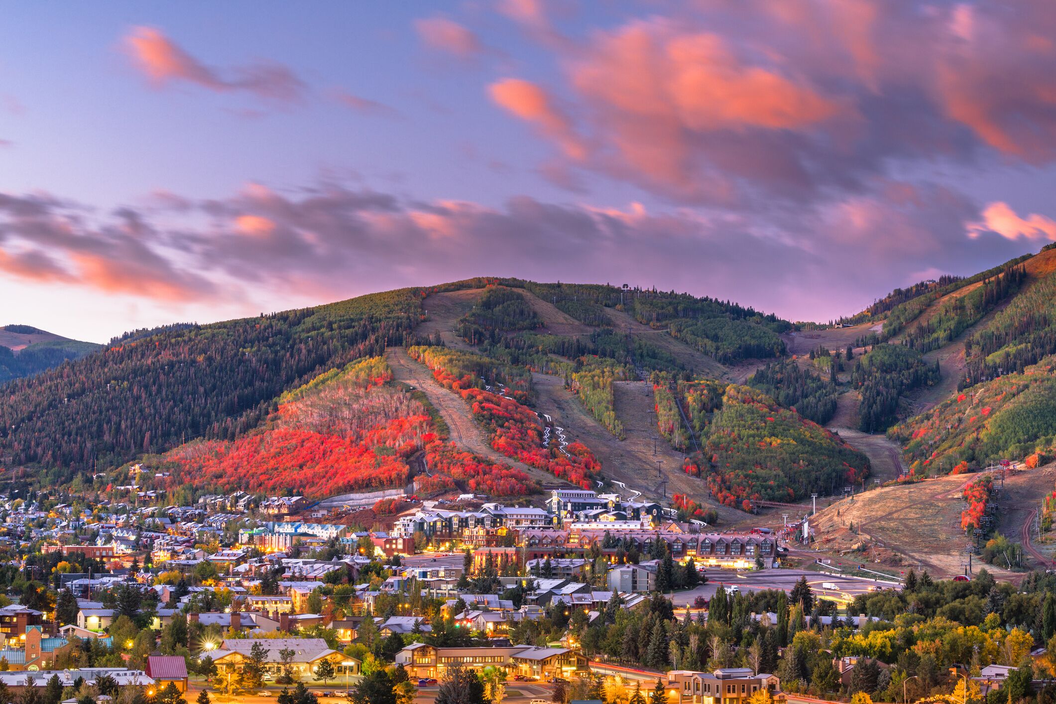 A town nestled in a valley with a mix of residential and commercial buildings, surrounded by hills with autumn foliage.