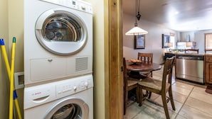 A laundry area with a Bosch washing machine and dryer, a dining table with chairs, and a kitchen area with a dishwasher and stove.