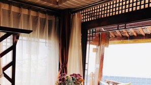 A cozy room with a sofa, a wooden table with a vase of flowers, and a bed with pillows.