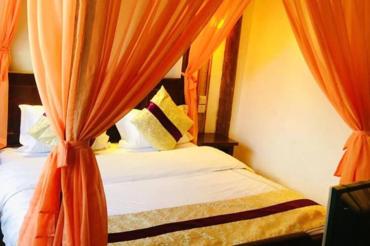 A bed with an orange canopy, white bedding, and a wooden headboard.