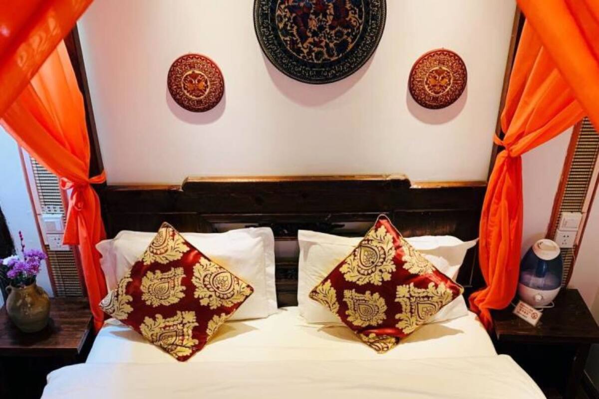 A bed with white bedding and two decorative pillows with intricate patterns.