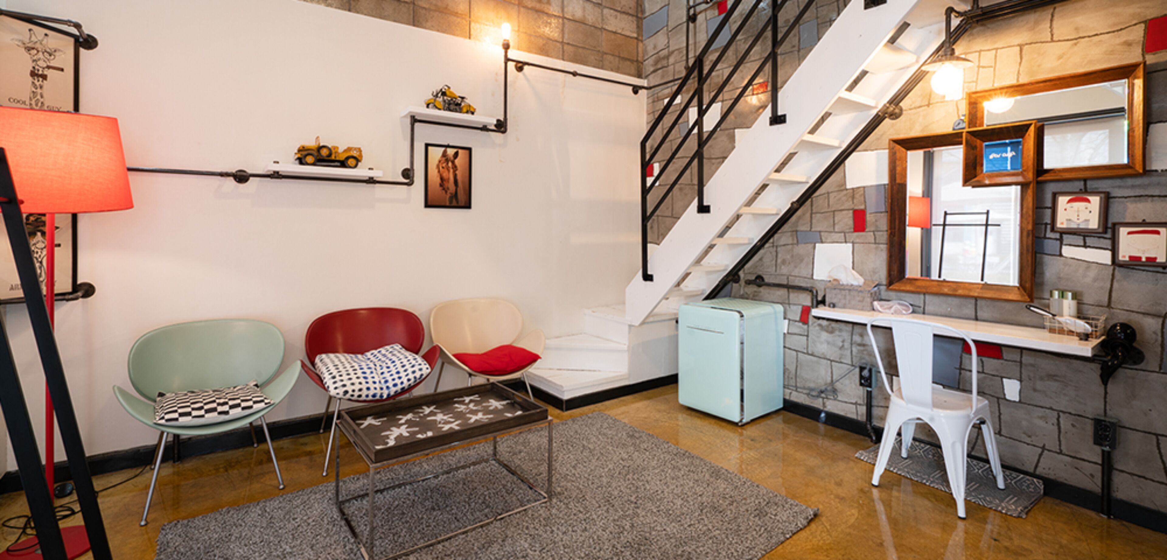 A modern interior with a staircase, seating area, and a desk.