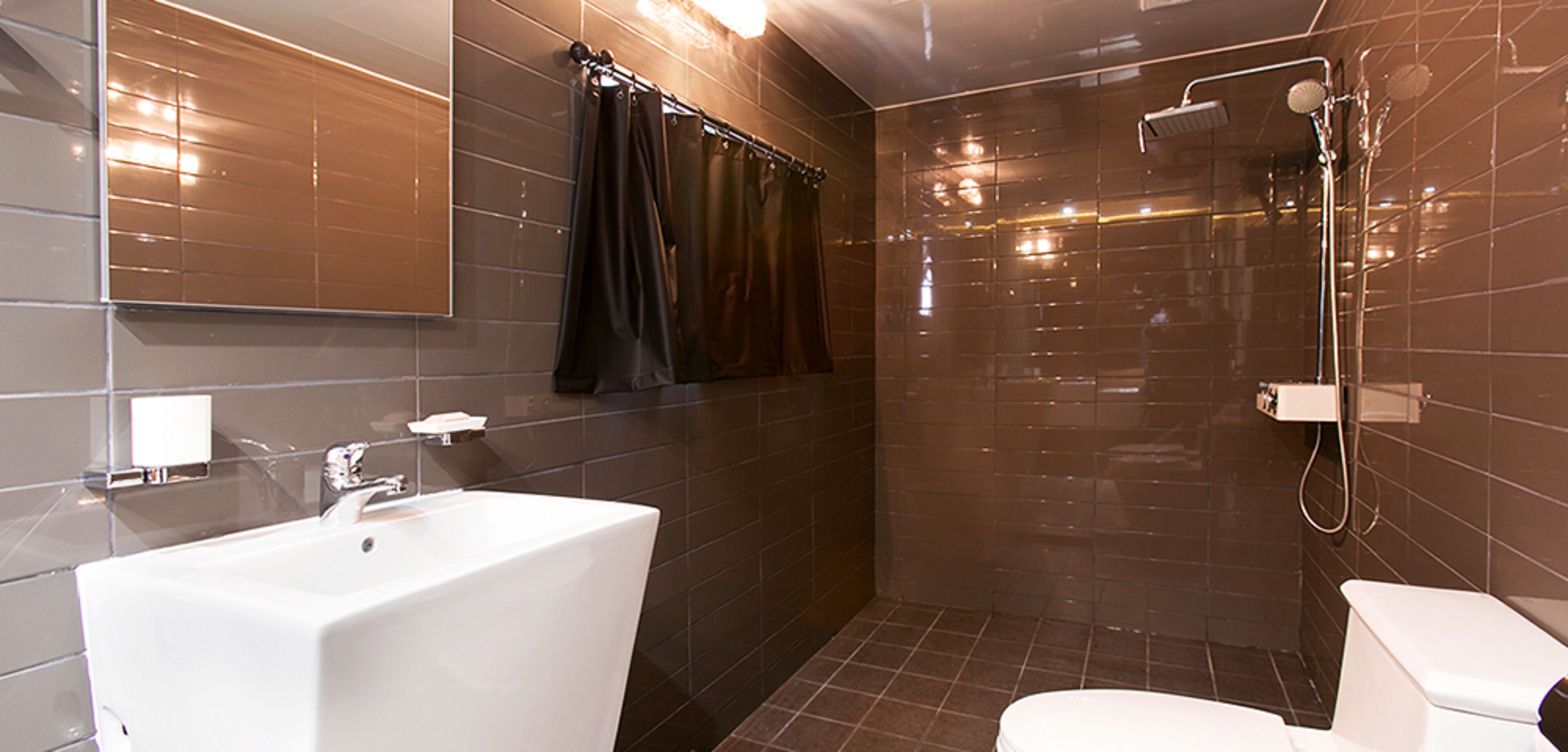 A modern bathroom with a large white sink, a toilet, and a shower area.