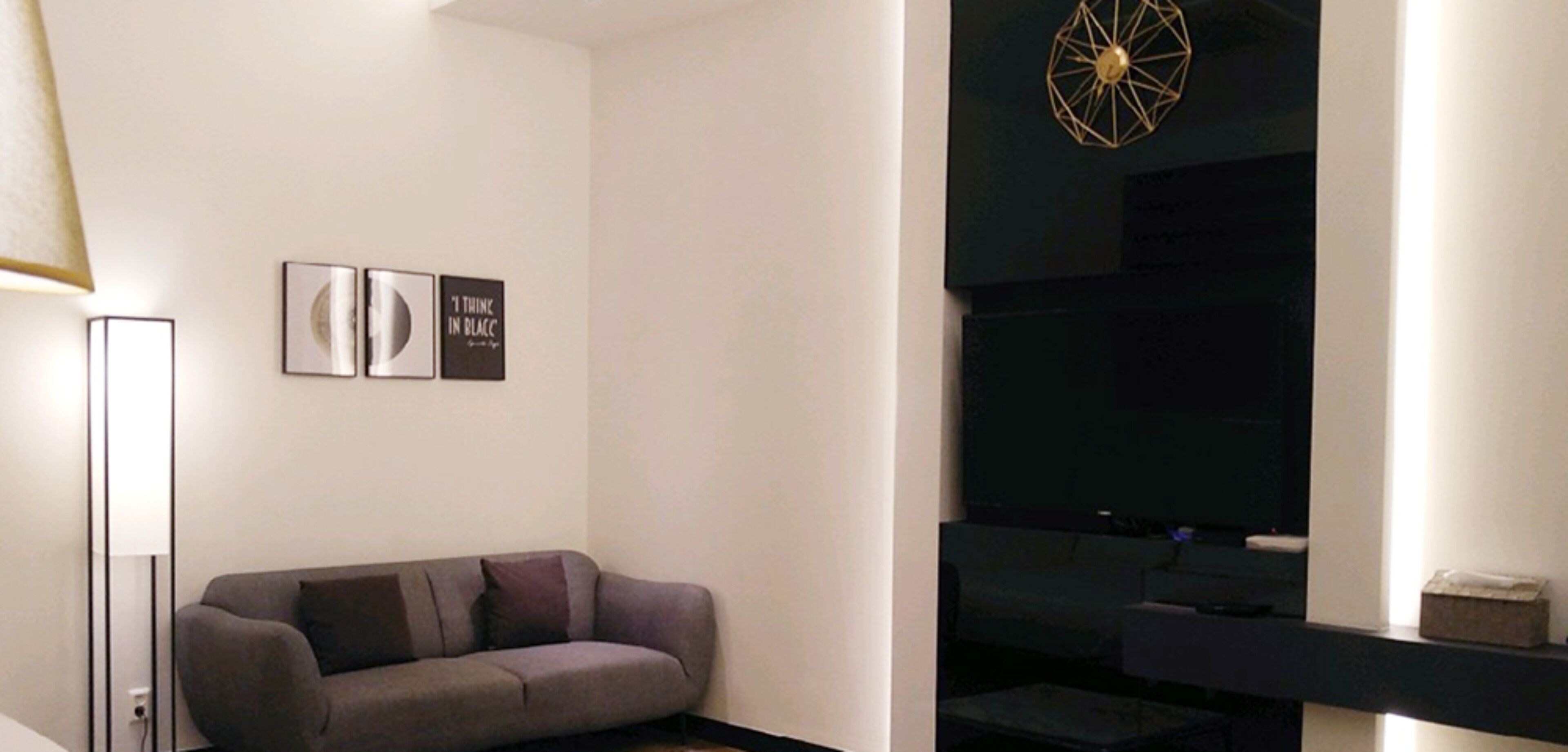 Una sala de estar moderna con un sofá gris, una lámpara de pie y obras de arte en la pared.