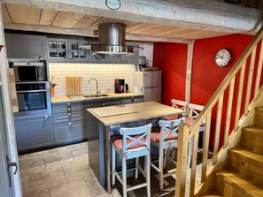 A compact kitchen with modern appliances, a dining area with a wooden table and chairs, and a red accent wall.