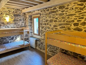 A room with stone walls, wooden bunk beds, a window, and a radiator. - Homerez - Chalet in Ascou (Ascou)