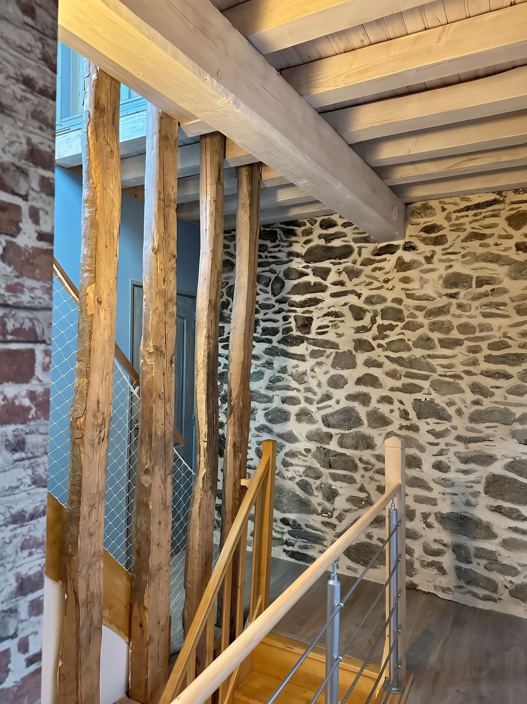 Una escalera con vigas de madera y una pared de piedra.