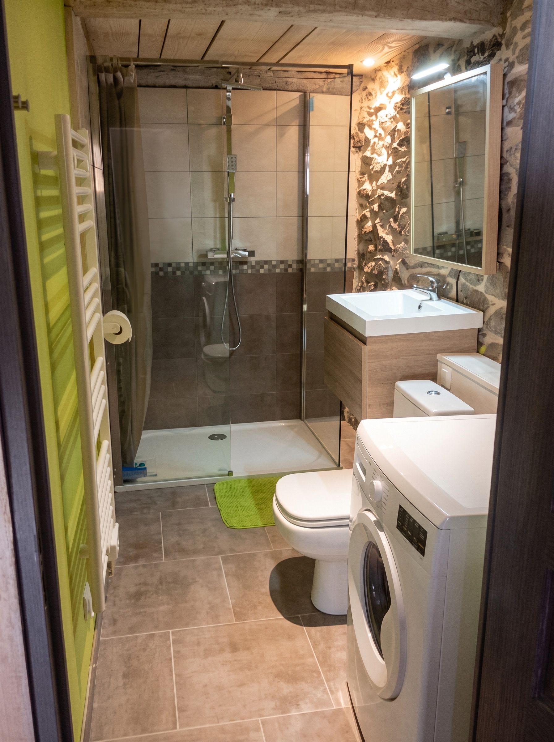 A compact bathroom with a shower, toilet, sink, and washing machine.