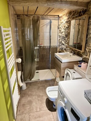 A bathroom with a shower, toilet, sink, and washing machine. - Homerez - Chalet in Ascou (Ascou)