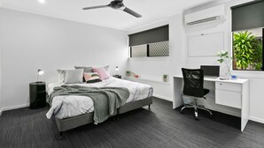 Un dormitorio moderno con cama, escritorio y silla.