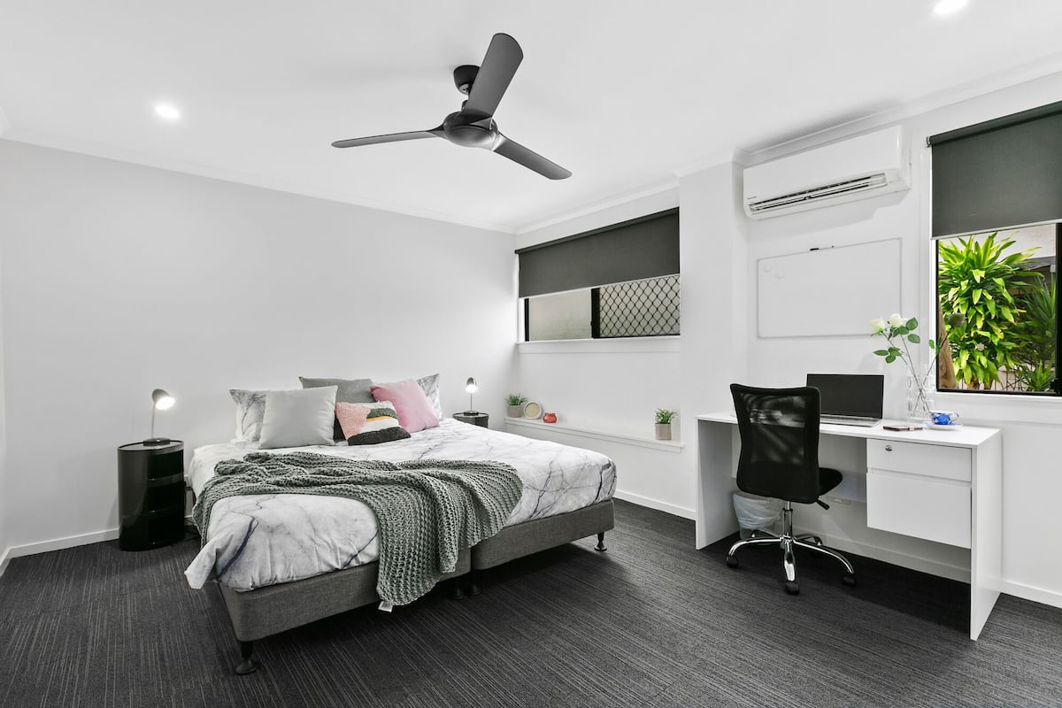 Een moderne slaapkamer met een bed, bureau en stoel.