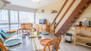 A dining area with a table set for four, a ceiling fan, and a staircase leading to an upper level. - Hippocampe by Interhome (Le Grau du Roi)