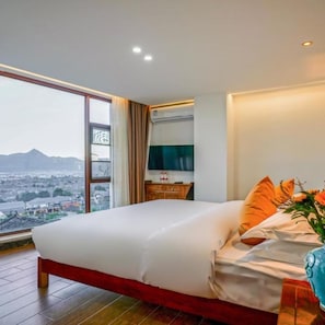 A hotel room with a large bed, a TV, and a view of a cityscape. - Floral Hotel Mi Yu Inn Lijiang (Lijiang)