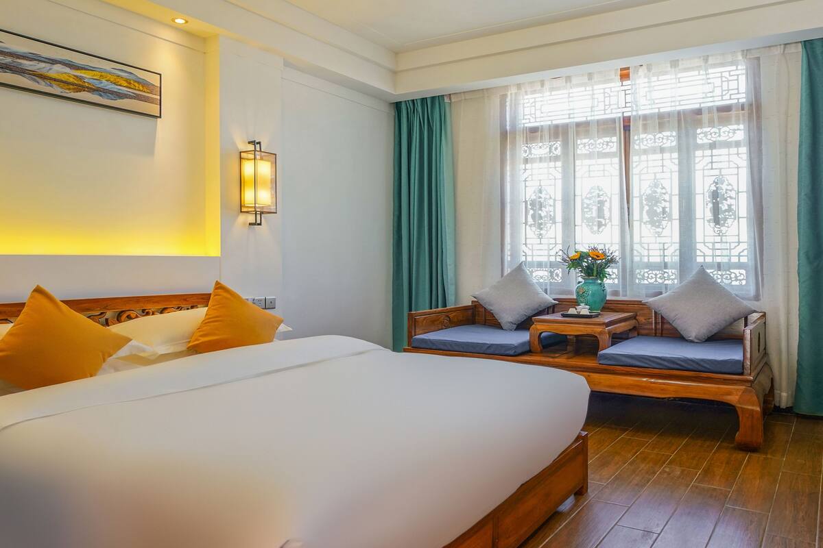 Una habitación de hotel con una cama grande, un sofá y una pequeña mesa con un jarrón de flores.