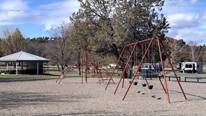 Un parc amb un tobogan, cadira d'oscalls i una glorieta.