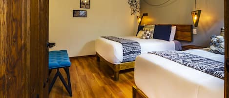 A room with two beds, a wooden bench, and a wall-mounted light fixture.