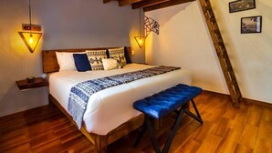 Un dormitorio con cama de madera, un banco y dos luces fijadas a la pared.