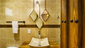 Un baño con tocador de madera, lavamanos y retrete.