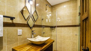 Un baño con tocador de madera, lavabo color beige y cabina de ducha de vidrio.