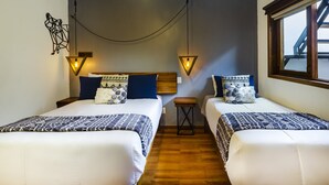 Habitación de hotel con dos camas, suelo de madera y ventana con vistas.