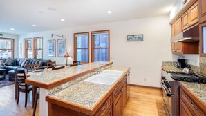 A modern kitchen with granite countertops, wooden cabinets, and a central island with a sink. - Downtown Telluride Townhome | Walk to Gondola | 3BR, Steam Shower, Parking (Telluride)