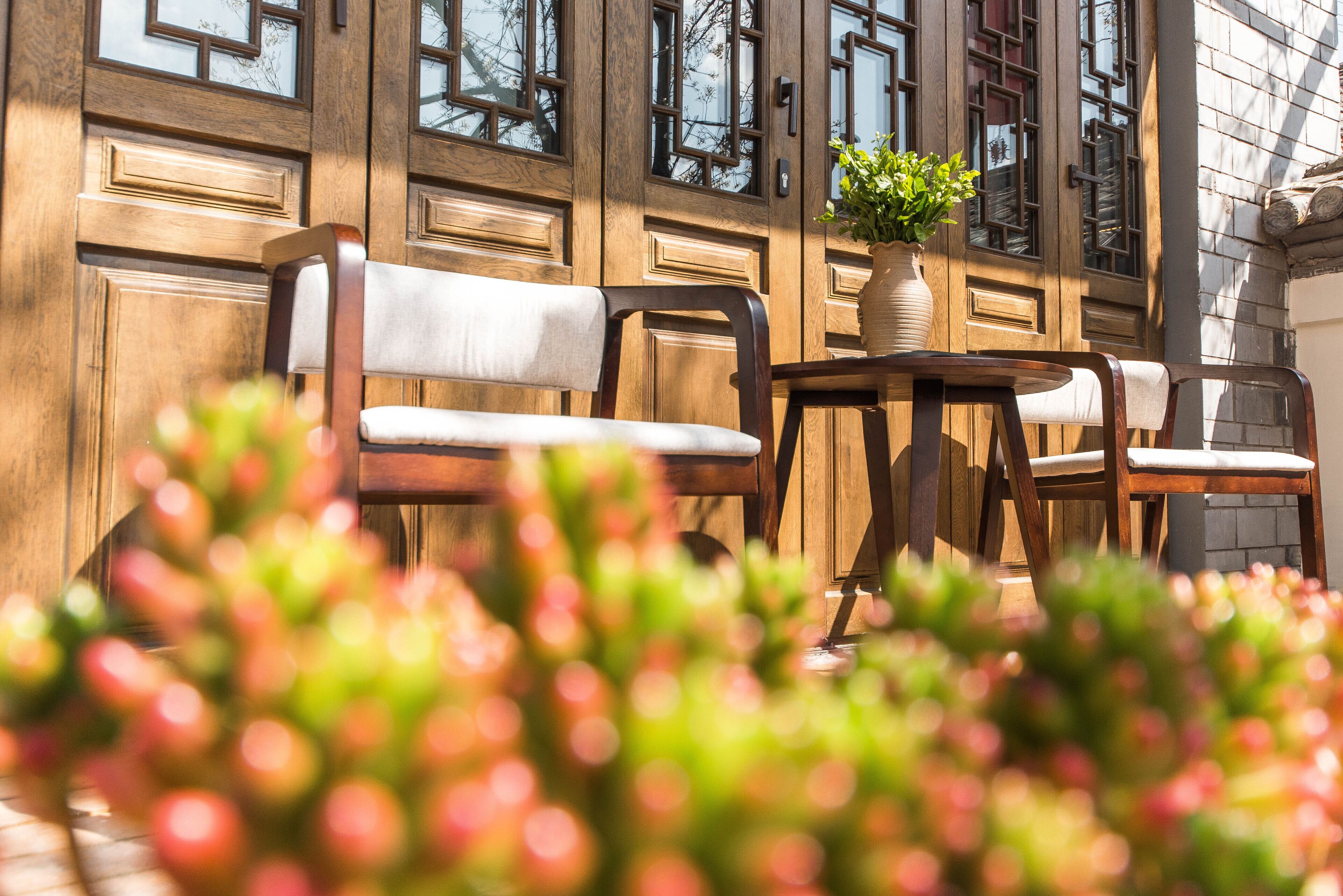 Un banc et une table en bois sont placés devant un bâtiment doté de grandes fenêtres.