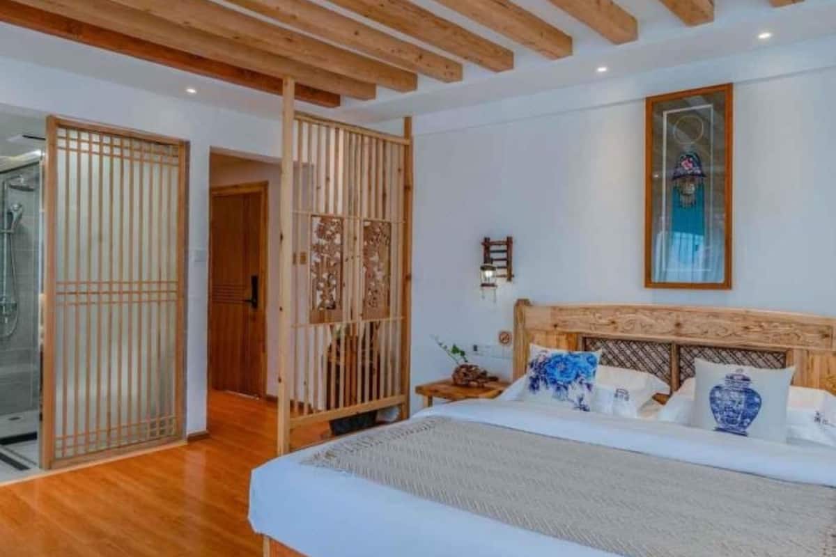 A bedroom with a wooden ceiling, a bed with blue and white pillows, and a wooden floor.
