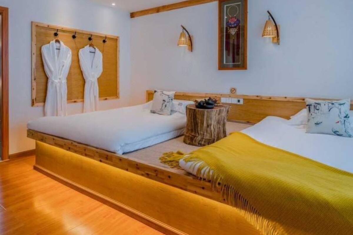 A bedroom with a wooden headboard, two beds, a wooden bench, and a wall-mounted robe rack.