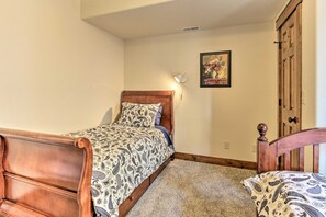 A bedroom with a bed, a nightstand, a wooden headboard, a wall-mounted light, and a door. - Rocky Mountain Hideaway | Scenic Views & Cozy Retreat (Estes Park)