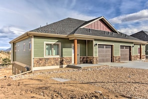 A single-story house with a stone foundation, a front porch, and a garage. - Rocky Mountain Hideaway | Scenic Views & Cozy Retreat (Estes Park)
