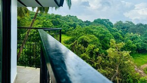 A balcony with a view of a lush green landscape and a clear sky. - Half Hotel (Candolim)