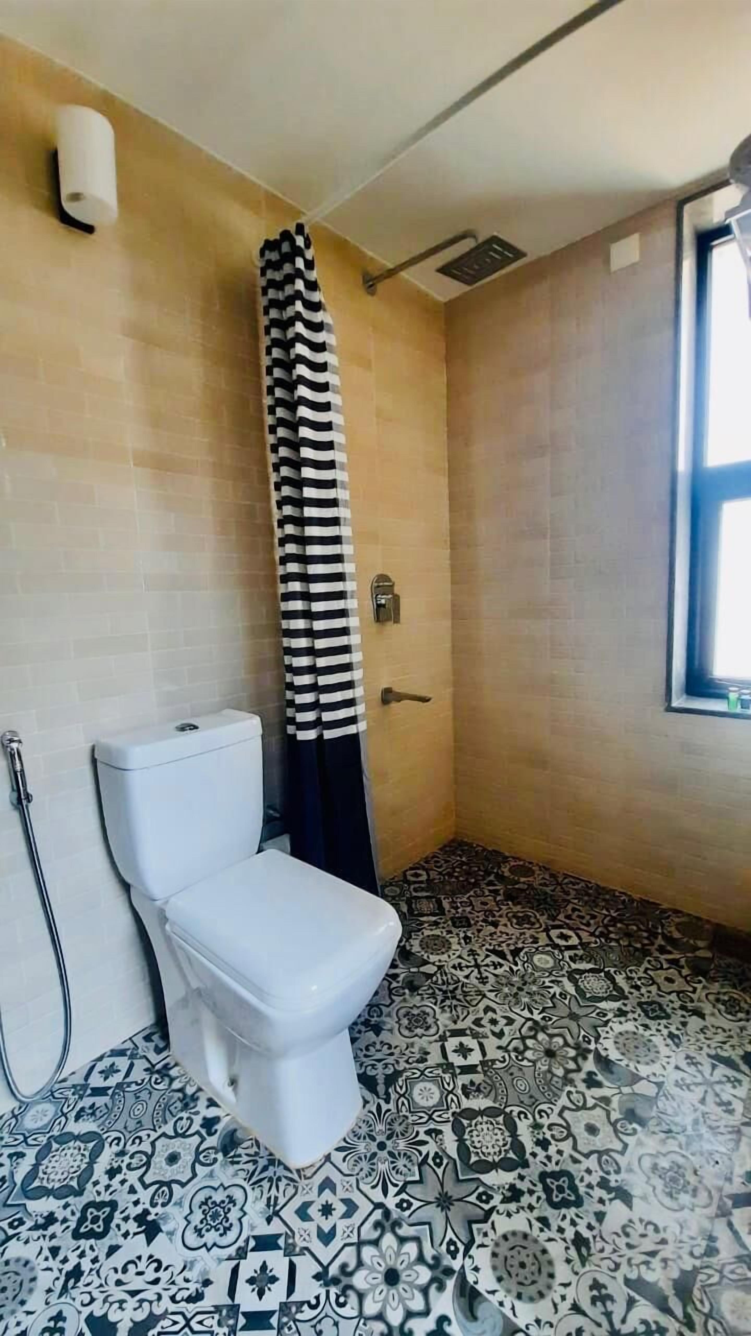 Une salle de bain avec des toilettes, une douche et un carrelage décoratif.